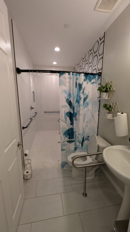 Accessible Bathrooms Wheelchair-accessible bathroom with roll-in shower and safety grab bars at Desert Willow Memory Care.